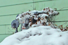 natural gas connections to a house covered in snow and unsafe leaves and debris