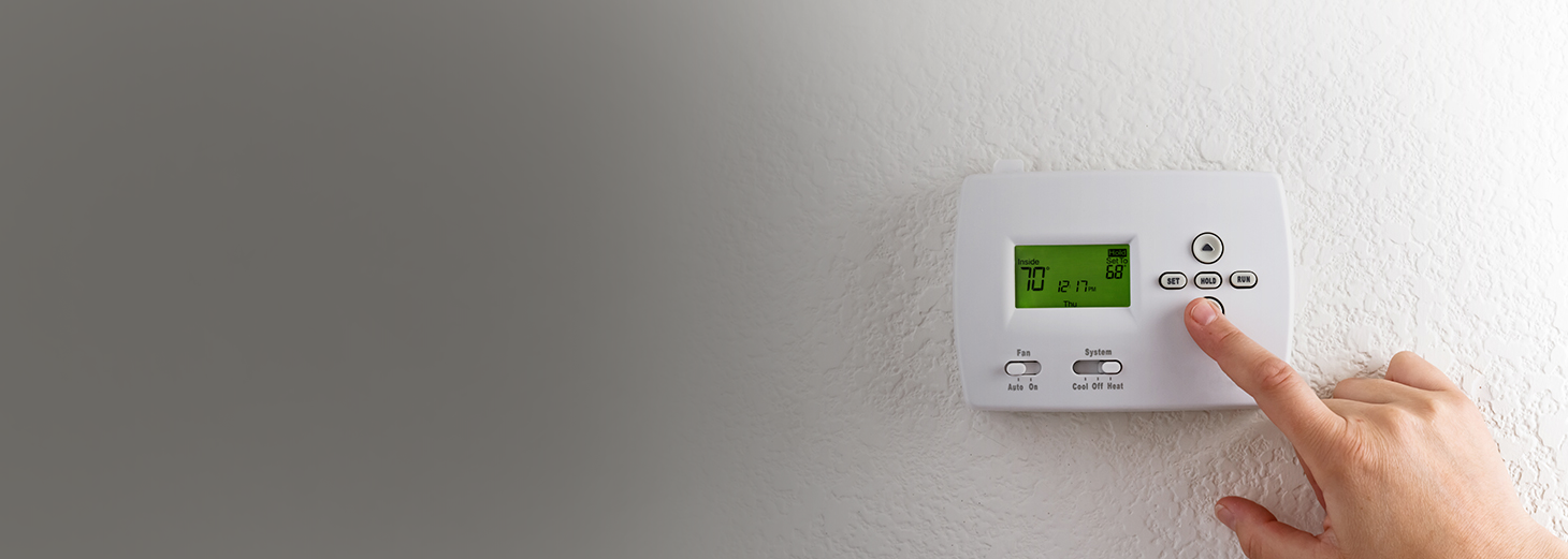 A hand adjusting a thermostat.